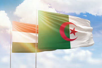 Sunny blue sky and flags of algeria and hungary