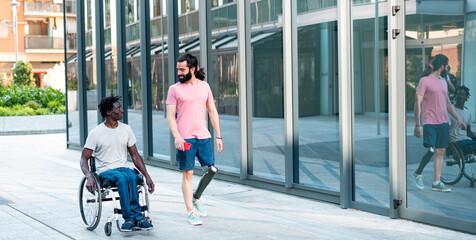 Multiracial friends walking in a disability friendly city - Two adult man speaking and walking in...