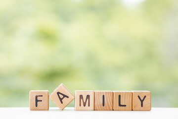 Family word is written on wooden cubes on a green summer background Closeup of wooden elements