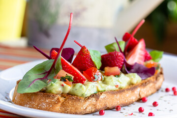 Keto diet avocado toast with strawberries, soft cheese, sesame seeds and herbs. healthy Breakfast or lunch. sandwich recipe mix media. top view, selective focus