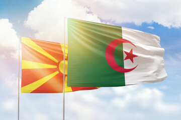 Sunny blue sky and flags of algeria and north macedonia
