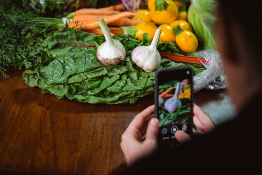 a person taking phone photos of a pile of vegetables