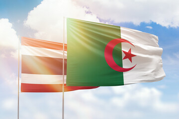 Sunny blue sky and flags of algeria and thailand