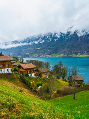 Fototapeta na wymiar Traditional Swiss houses on hillsside on Lake Brienz in Iseltwald Switzerland