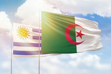 Sunny blue sky and flags of algeria and uruguay