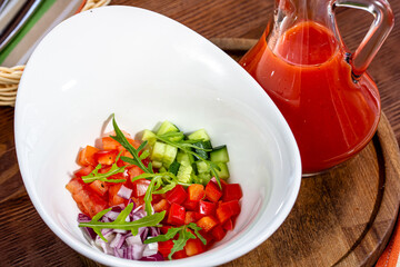 Tasty appetizing summer tomato soup puree gazpacho with tomatoes and cucumbers served in bowl