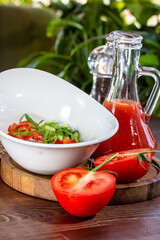 Tasty appetizing summer tomato soup puree gazpacho with tomatoes and cucumbers served in bowl