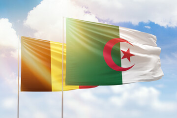 Sunny blue sky and flags of algeria and belgium