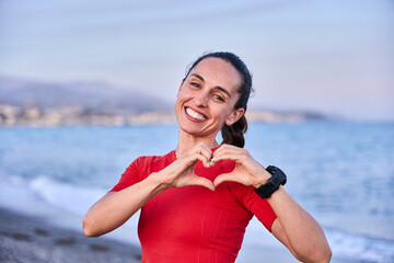 young athlete in red shirt and braid standing happily posing and showing a heart with her hands