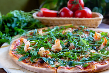 Delicious rustic Italian pizza with grilled Adriatic shrimps, mozzarella, sun dried tomatoes, arugula and parmesan cheese