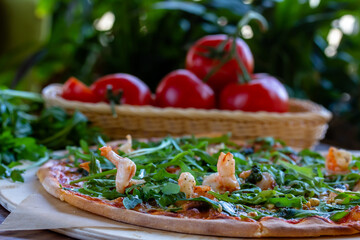 Obraz na płótnie Canvas Delicious rustic Italian pizza with grilled Adriatic shrimps, mozzarella, sun dried tomatoes, arugula and parmesan cheese