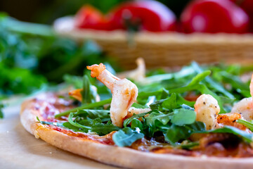 Delicious rustic Italian pizza with grilled Adriatic shrimps, mozzarella, sun dried tomatoes, arugula and parmesan cheese