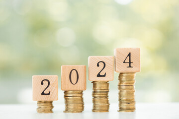 stack of coins on wooden table with new year message 2024 business growth new beginning