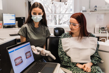 The famale dentist shows digital model of female patient's teeth made by 3d scanner. Teeth care concept.