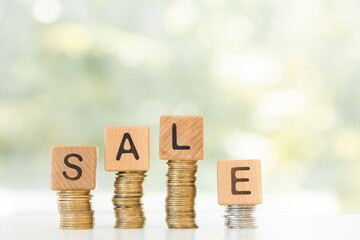 Word sale and stack coins on green background.