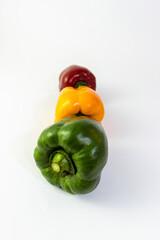Natural green paprika in front of yellow and red bell peppers