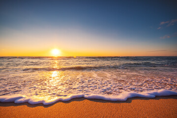 Fototapeta na wymiar Beautiful sunrise over the sea waves and beach. Island in the ocean.