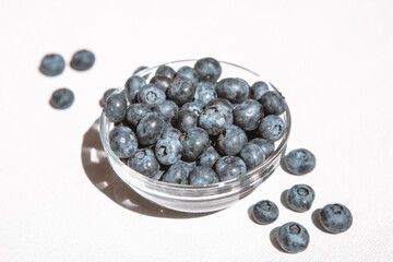Fresh blueberries in bowl and heap of berries on white table, healthy summer food