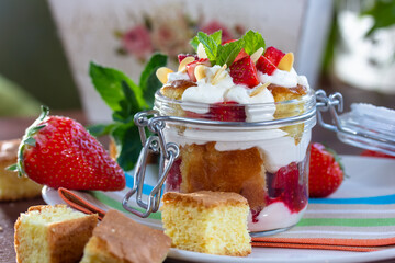 Layered Dessert of chocolate sponge cake, whipped cream or ricotta and fresh strawberries in a glass bowl. Trifle. Delicious gourmet breakfast.