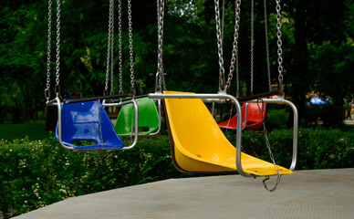 Pretty swing in a park with a different colour seats. Background picture.
