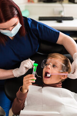 Dentist examining little boy's teeth in clinic, kids holding a hourglass,