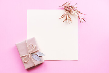 Fototapeta na wymiar Creative layout made of green leaves with diy gift box on pink background. Flat lay. Nature concept