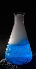 Erlenmeyer flask with a blue liquid and smoke which has been created by a chemical reaction....