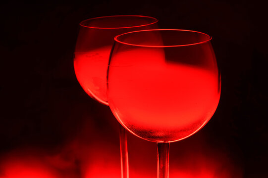 Two Glasses of a Red Alcoholic Cocktail on Dark Background with smoke and backlight. Very dangerous fire cocktail - close up photo. Background picture.