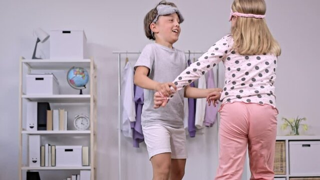 Sister and brother dressed in pyjamas are dancing together. Slow motion.