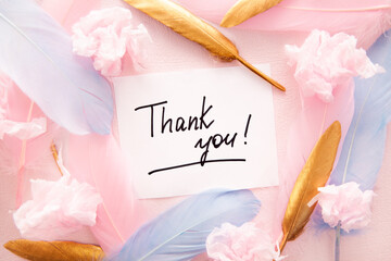 Thank you card on pink background with golden and blue feathers, decorations, thankfulness concept	