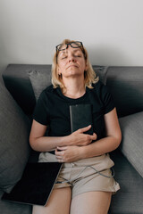 Middle age mature woman sleeping with book on the couch, home daydreaming 