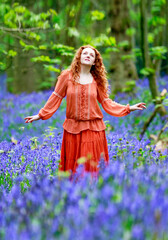 Fototapeta na wymiar Bright and Bon Vivant woman looking up in a bluebell wood