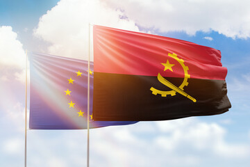 Sunny blue sky and flags of angola and european union