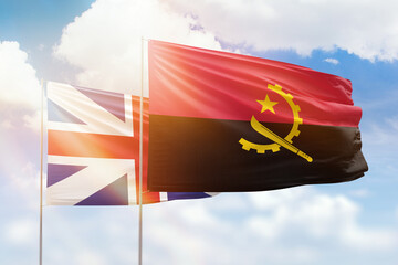 Sunny blue sky and flags of angola and great britain