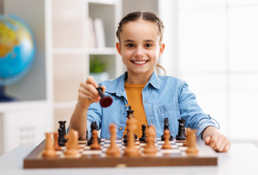 Happy girl playing chess at school