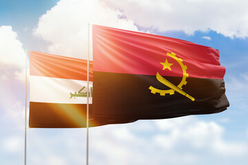 Sunny blue sky and flags of angola and iraq