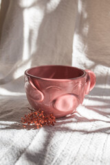 Obraz na płótnie Canvas handmade ceramic cup in the shape of a pig on cloth and dried flowers