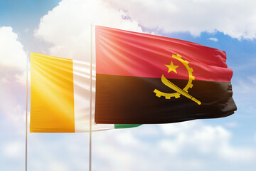 Sunny blue sky and flags of angola and ivory coast