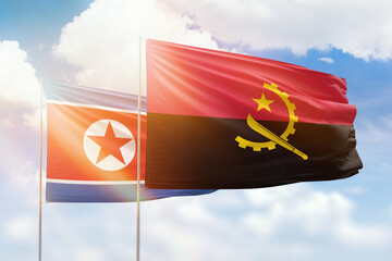 Sunny blue sky and flags of angola and north korea