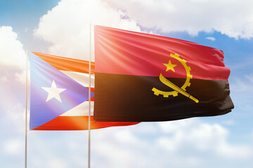 Sunny blue sky and flags of angola and puerto rico