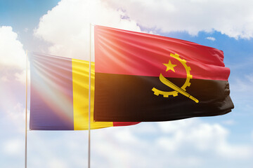 Sunny blue sky and flags of angola and romania
