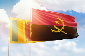Sunny blue sky and flags of angola and sri lanka