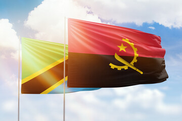 Sunny blue sky and flags of angola and tanzania