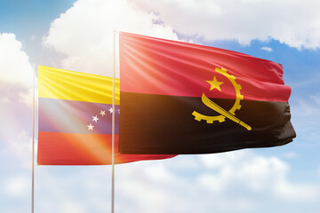 Sunny blue sky and flags of angola and venezuela