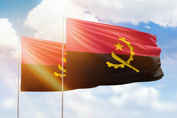 Sunny blue sky and flags of angola and angola