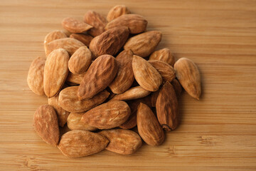 Unshelled almonds, coarse-grained raw almonds on a wooden floor. Unprocessed healthy nuts concept.