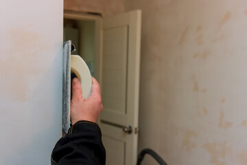 Apartment renovation with worker applies checking levelling to wall a using grinding spatula