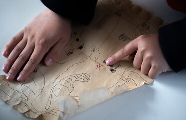 Children's hands hold a treasure map. Search for treasure with a child.Active outdoor games. In...