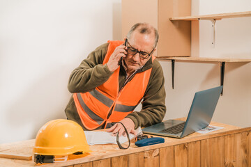 Contractor construction engineer reviewing the development of the work and talking by cell phone with the supplier.