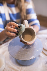 woman working a handmade ceramic cup in her workshop